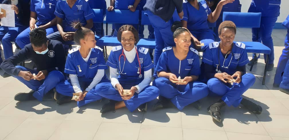 Group of PMT students in blue uniforms gathered together on the ground.
